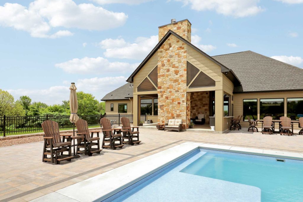 Newly constructed house with outdoor furniture around a pool.