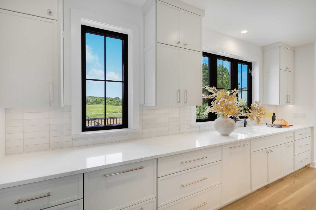 White kitchen, with white cupboards, white countertop and black framed windows above the sink. 3761 William Way Independence Mn 55359 44